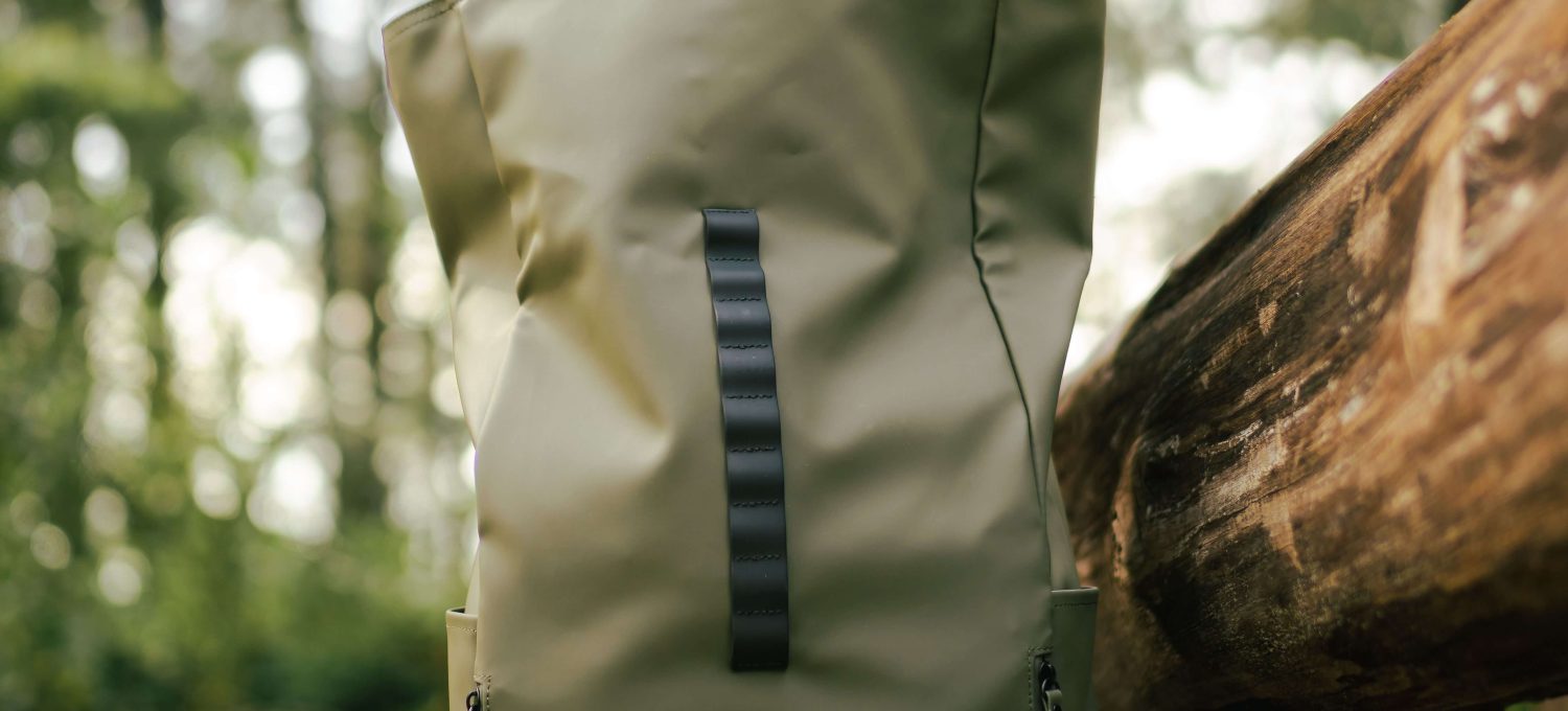 Fotógrafo sacando una cámara Sony de una mochila ligera y compacta de color verde oliva en un entorno natural, simbolizando la preparación para la aventura fotográfica al aire libre, con el enfoque en la facilidad de transporte y la funcionalidad del equipo.