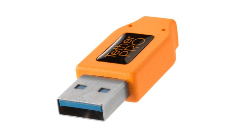 Conector USB naranja de la marca Tether Pro, diseñado para mejorar la conectividad en equipos profesionales de fotografía y vídeo, mostrado sobre fondo blanco.
