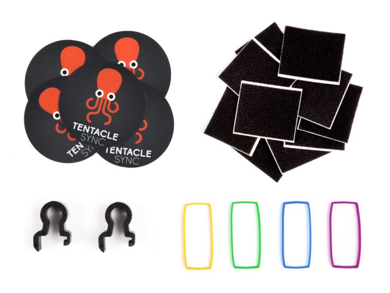 Conjunto de accesorios para organización de equipos de fotografía y vídeo, incluyendo parches de velcro adhesivo, etiquetas de colores, clips de sujeción y pegatinas de Tentacle Sync.