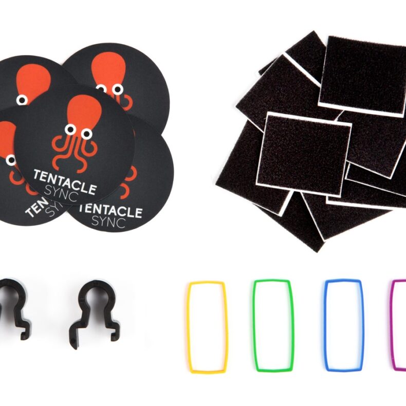 Conjunto de accesorios para organización de equipos de fotografía y vídeo, incluyendo parches de velcro adhesivo, etiquetas de colores, clips de sujeción y pegatinas de Tentacle Sync.